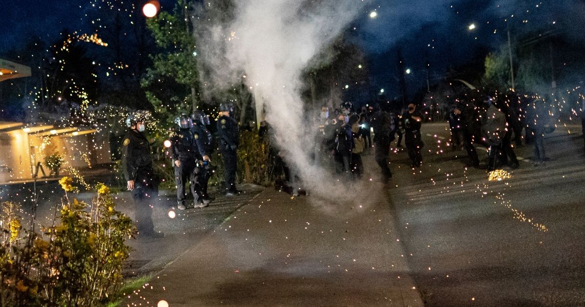 A firework explodes near Portland police officers during a protest on April 12, 2021, in Portland, Oregon.