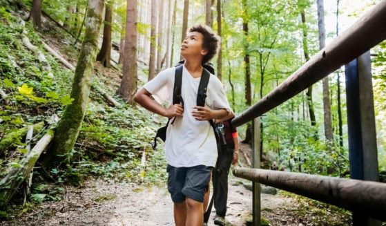 This stock photo portrays a boy enjoying an outdoors hiking trail with his family. This week, Outside magazine published a piece concerning the "nature gap" that is perpetuating systemic racism.