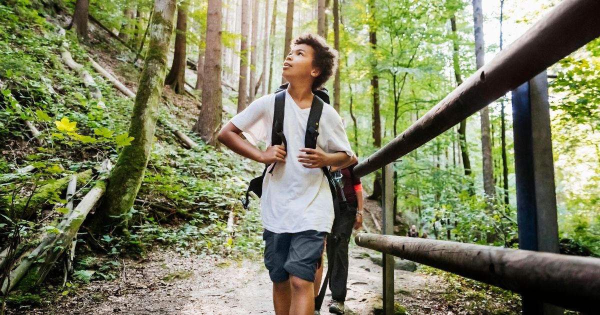 This stock photo portrays a boy enjoying an outdoors hiking trail with his family. This week, Outside magazine published a piece concerning the "nature gap" that is perpetuating systemic racism.