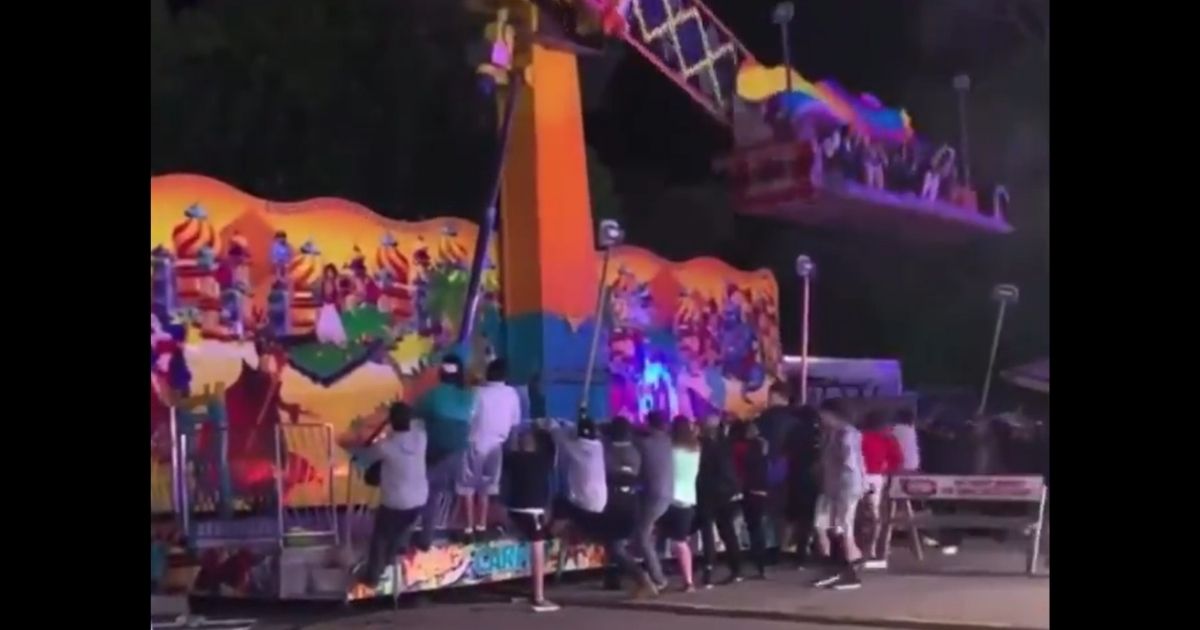Attendees at the 95th annual National Cherry Festival in Grand Traverse County, Michigan, jump in to help when the Magic Carpet Ride appears as if it's going to tip over.