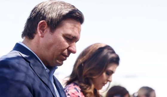 Republican Florida Gov. Ron DeSantis and his wife, Casey, pray at a memorial for those missing outside the 12-story Champlain Towers South condo building that partially collapsed, on Saturday in Surfside, Florida.