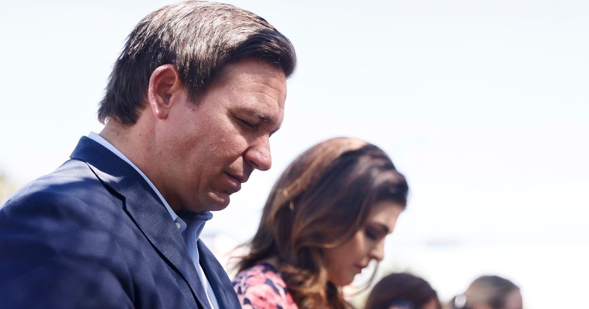 Republican Florida Gov. Ron DeSantis and his wife, Casey, pray at a memorial for those missing outside the 12-story Champlain Towers South condo building that partially collapsed, on Saturday in Surfside, Florida.