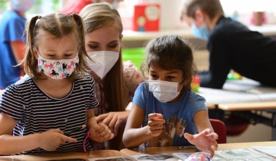 Pupils, wearing face masks, listen to their teacher during a summer project at the primary school Sonnenschule in Beckum, western Germany, on July 6, 2021.