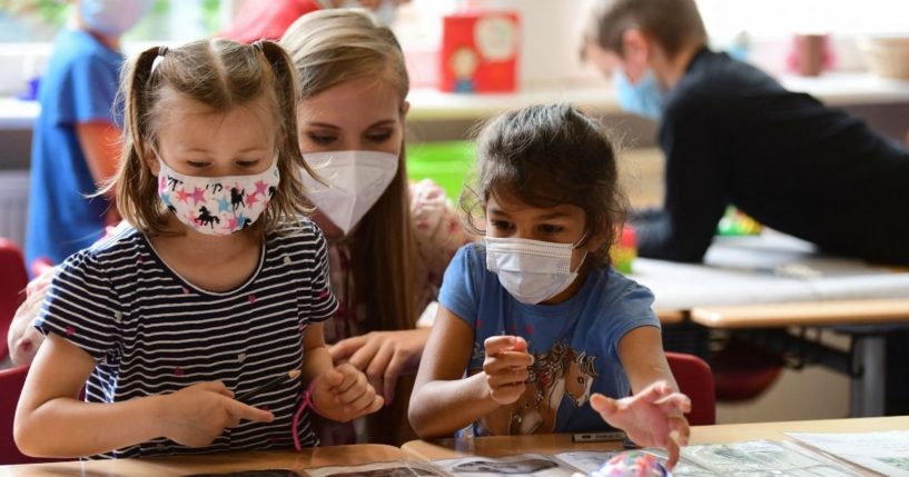 Pupils, wearing face masks, listen to their teacher during a summer project at the primary school Sonnenschule in Beckum, western Germany, on July 6, 2021.