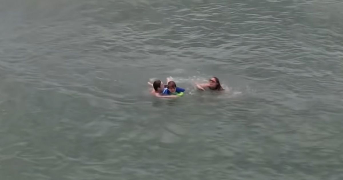 Travis Shrout helping Ashley Batchelor and her son Conner get back to shore after they got caught in a riptide.