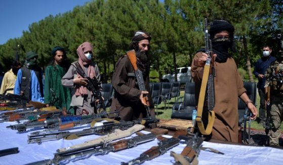 Taliban fighters put down their weapons as they surrender to join the Afghanistan government during a ceremony in Herat on June 24, 2021.