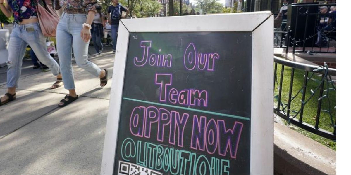 Pedestrians walk past a sign inviting people to apply for employment at a shop in Boston's fashionable Newbury Street neighborhood on Monday.