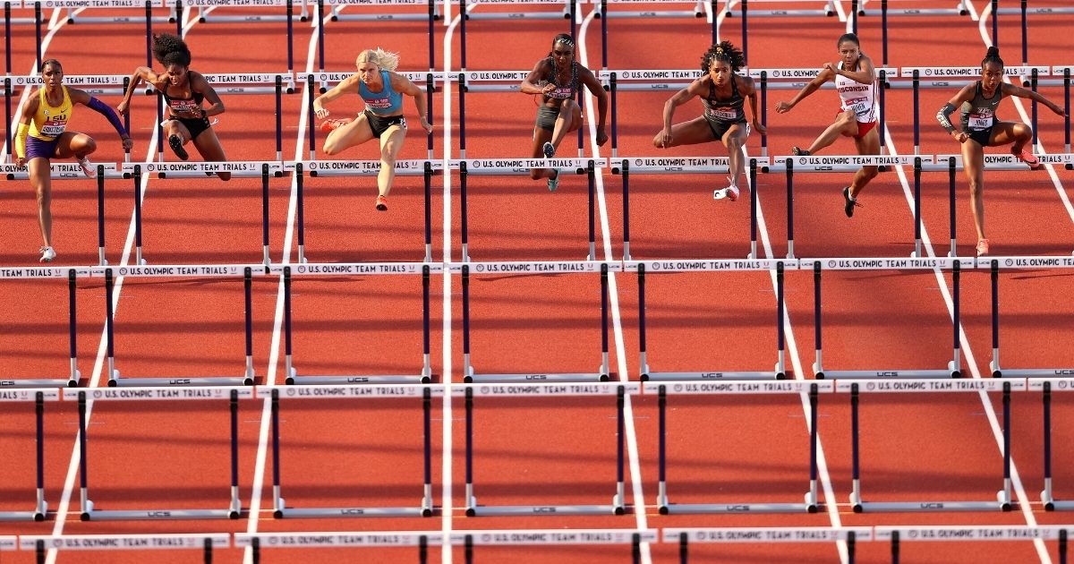 A group of female athletes runs over hurdles at the Hayward Field in Eugene, Oregon, on June 19, 2021.