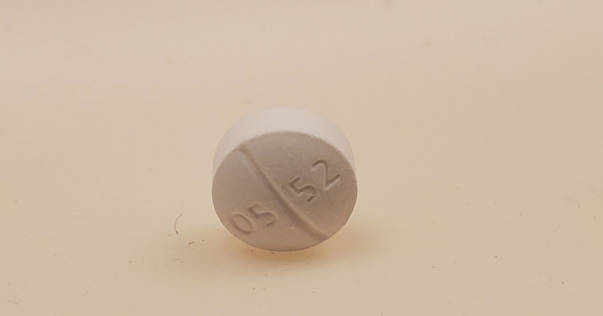 Close-up of a white Oxycodone Hydrochloride 5 mg pill, marked 05 52, resting on its edge on a white surface, photographed in Lafayette, California, May, 2021.