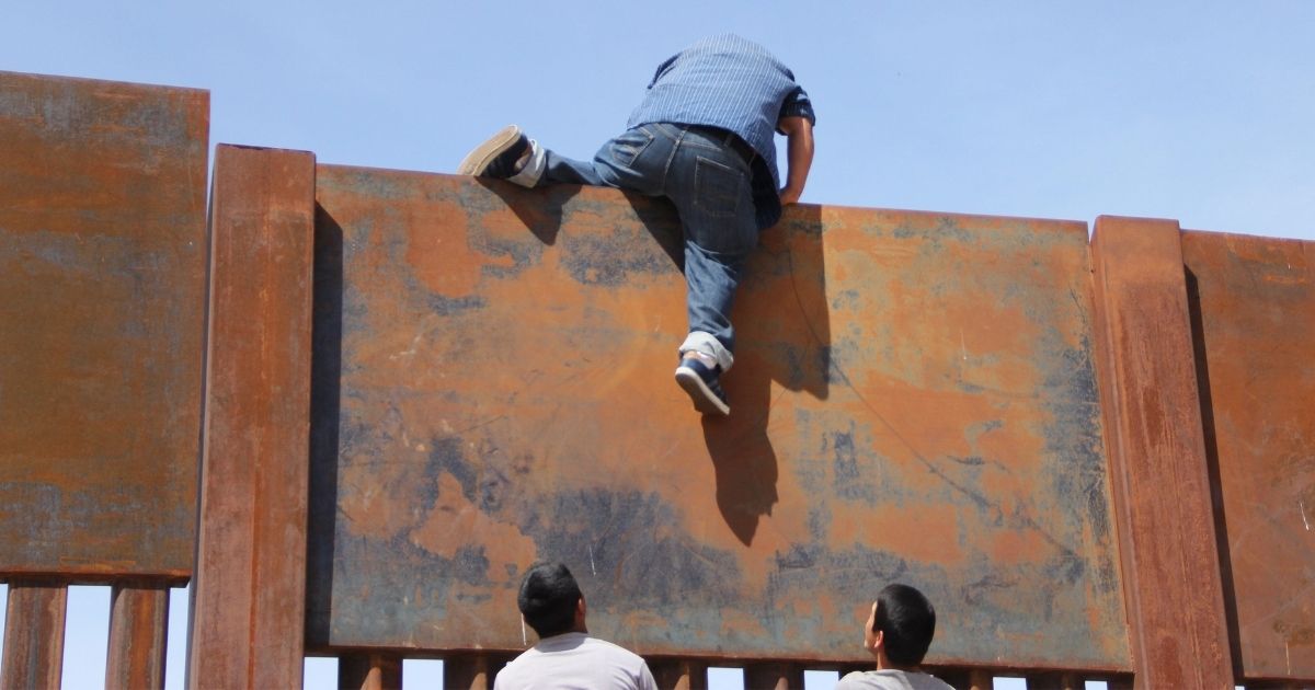 Young Mexicans help a compatriot to climb the metal wall that divides the border between Mexico and the U.S. to cross illegally to Sunland Park, New Mexico, from Ciudad Juarez, Mexico, on April 6, 2018.