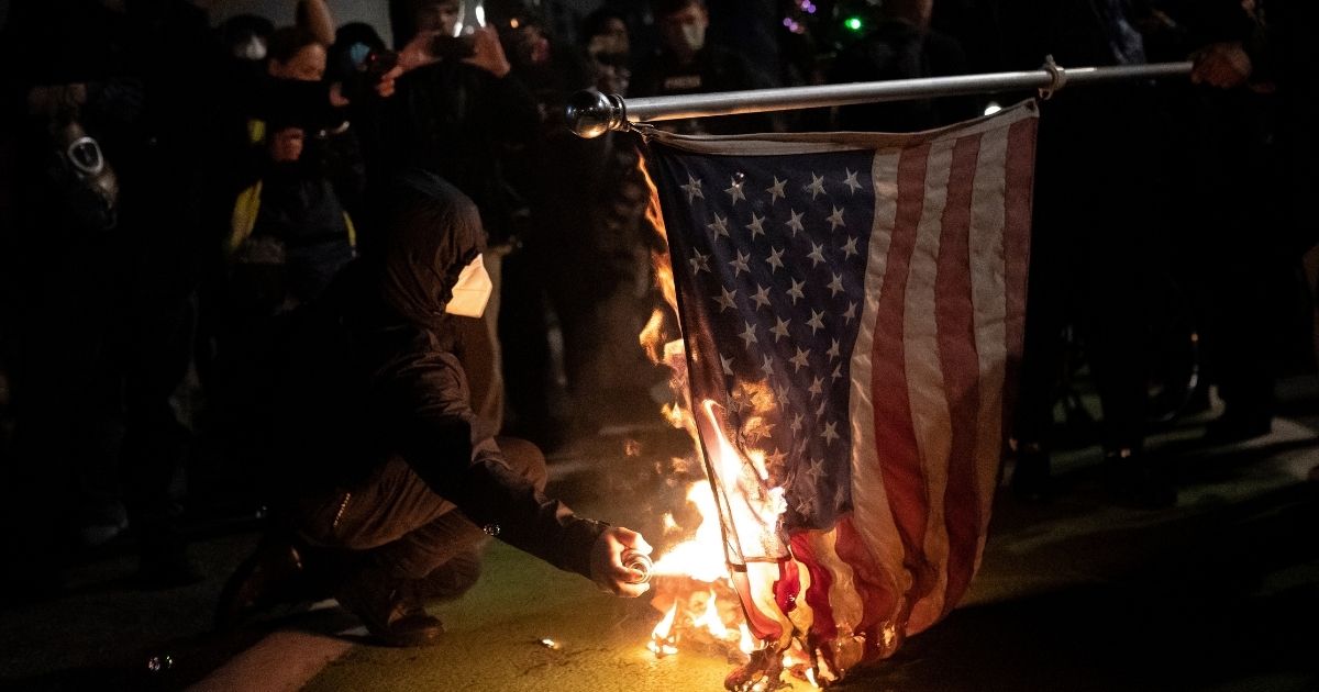 Black bloc protesters burn an American flag on Nov. 4, 2020, in Portland, Oregon.