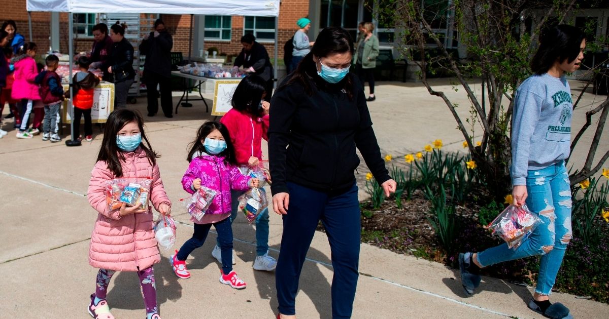 Children, some wearing face masks, pick up free lunch at Kenmore Middle School in Arlington, Virginia on March 16, 2020, after schools in the area closed due to the coronavirus outbreak.