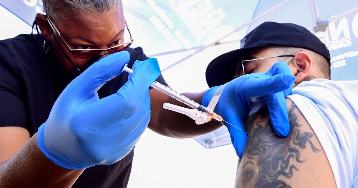 Nurse Eon Walk, left, administers the Pfizer-BioNTech COVID-19 vaccine at a mobile vaccine clinic hosted by Mothers in Action and operated by the Los Angeles County of Public Health on July 16, 2021, in Los Angeles.