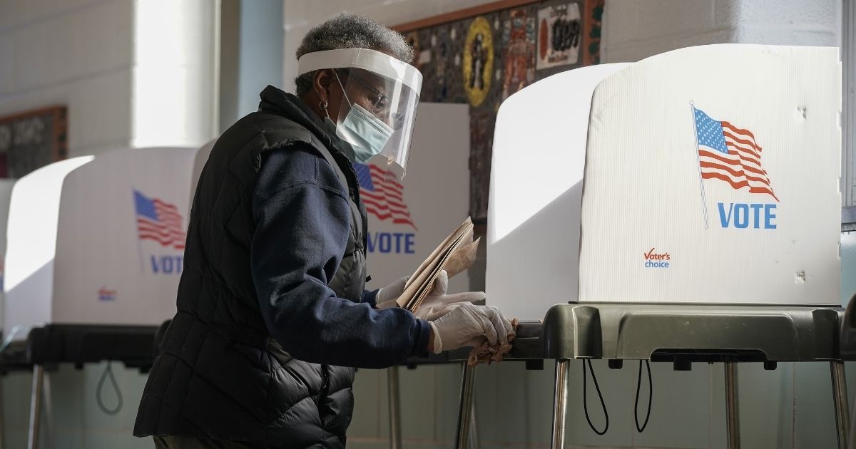 A poll worker cleans a voting booth between voters as residents of Baltimore City cast their votes in the U.S. presidential and local congressional elections at Western High School on Nov. 3, 2020, in Baltimore.