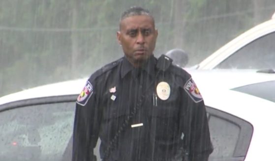 Mount Vernon Police Department officer Newman Brazier stands in the rain during a funeral procession for a 100-year-old World War II veteran.