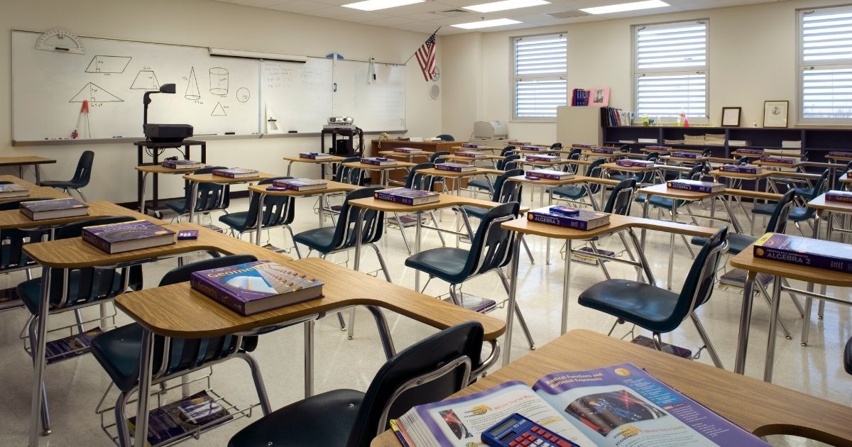 An empty classroom is seen in the stock image above.