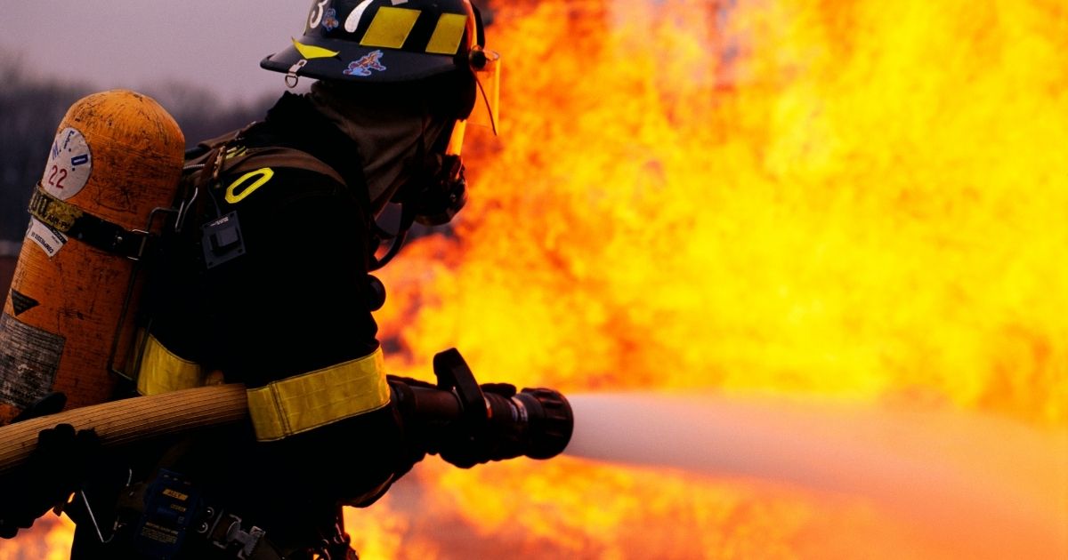 A firefighter sprays water at a fire in this stock image.