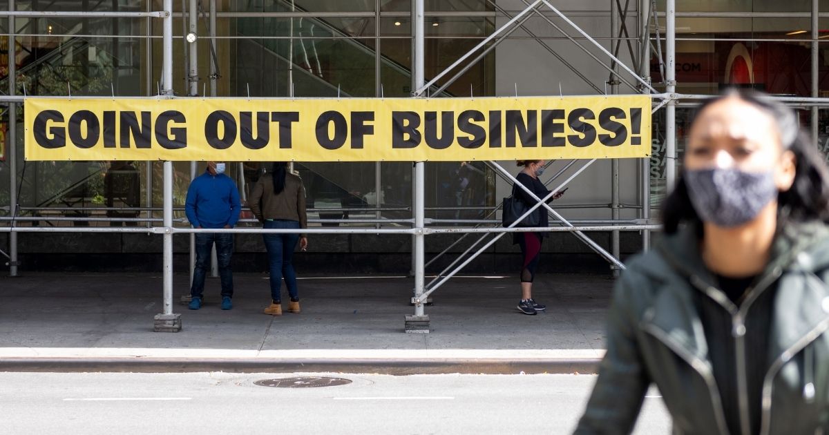 A woman wearing a mask walks by a "going out of business" sign on Sept. 20, 2020, in New York City.
