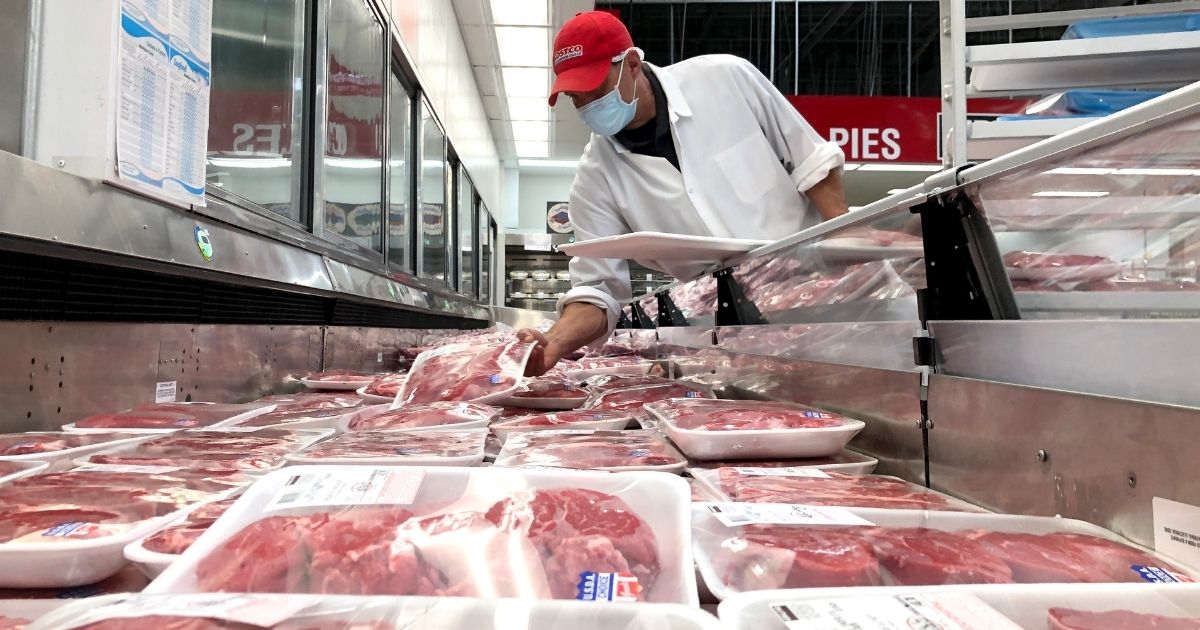 A butcher stocks a display case with packages of steaks at a Costco store on May 24, 2021, in Novato, California.