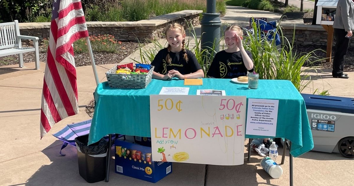 Scarlet and Addyson with the lemonade stan they ran to help raise funds for a fallen officer.
