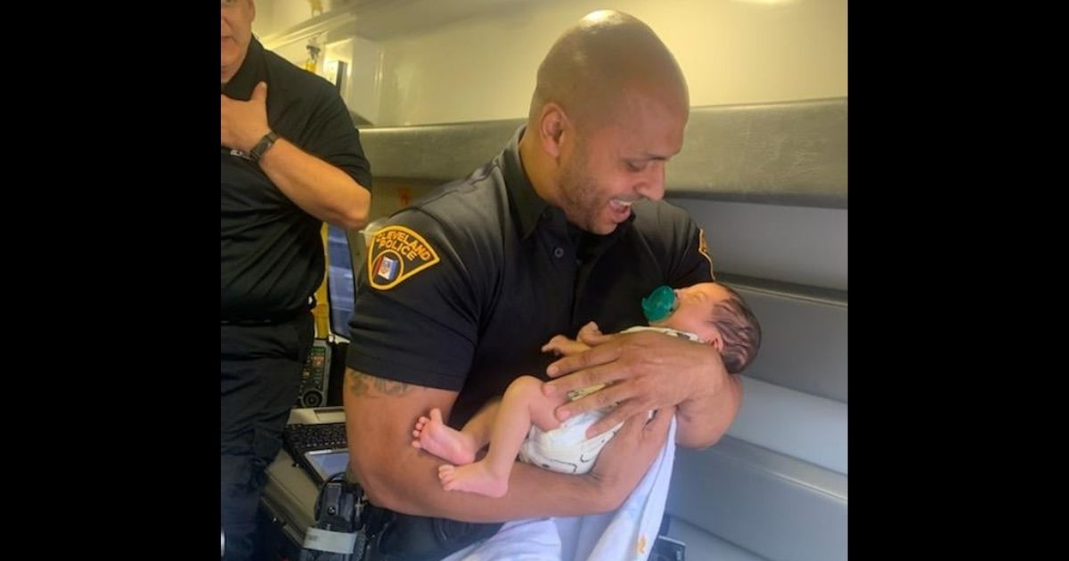 A Cleveland police officer holds the 6-week-old baby found Wednesday after being driven off with Tuesday night.