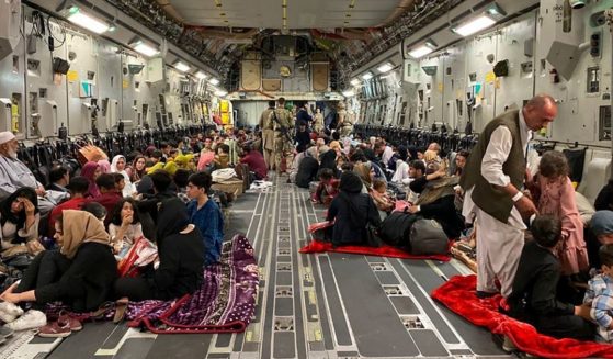 Afghan people sit inside a U.S. military aircraft to leave Afghanistan, at the military airport in Kabul on Thursday after Taliban's military takeover of Afghanistan.