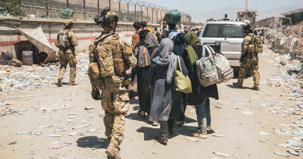 In this photo provided by the U.S. Marine Corps, Italian coalition forces assist and escort evacuees for onward processing during an evacuation at Hamid Karzai International Airport in Kabul, Afghanistan, on Tuesday.