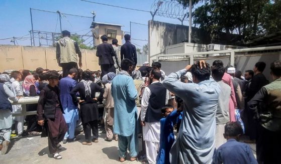 People gather outside the French embassy in Kabul on Tuesday waiting for a chance to leave Afghanistan as the Taliban takes over.