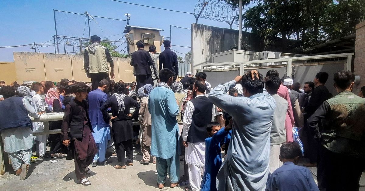 People gather outside the French embassy in Kabul on Tuesday waiting for a chance to leave Afghanistan as the Taliban takes over.