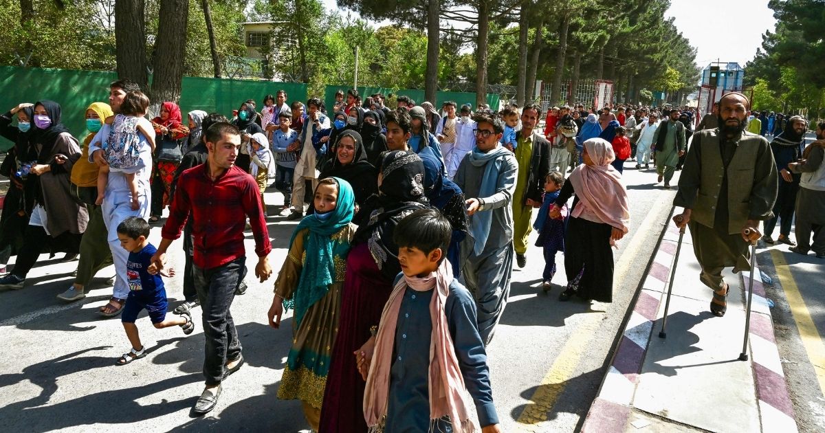 Afghan people move toward the Kabul airport to leave Kabul on Monday after a stunningly swift end to Afghanistan's 20-year war, as thousands of people mobbed the city's airport trying to flee the group's feared hardline brand of Islamist rule.