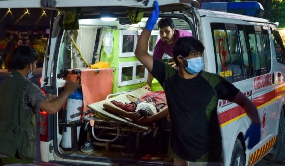 Medical staff bring an injured man to a hospital in an ambulance after two powerful explosions killed multiple people outside the airport in Kabul, Afghanistan, on Thursday.