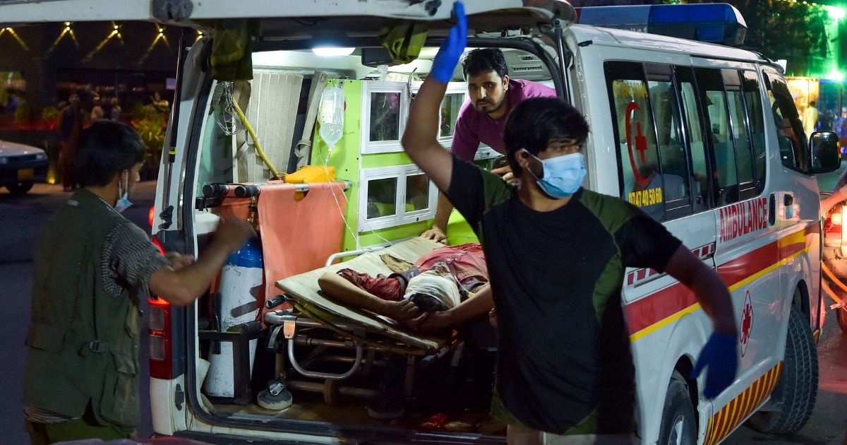Medical staff bring an injured man to a hospital in an ambulance after two powerful explosions killed multiple people outside the airport in Kabul, Afghanistan, on Thursday.