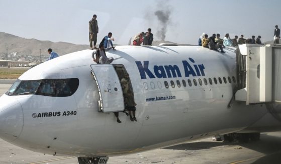 Afghans climb atop a plane at the Kabul airport on Monday.