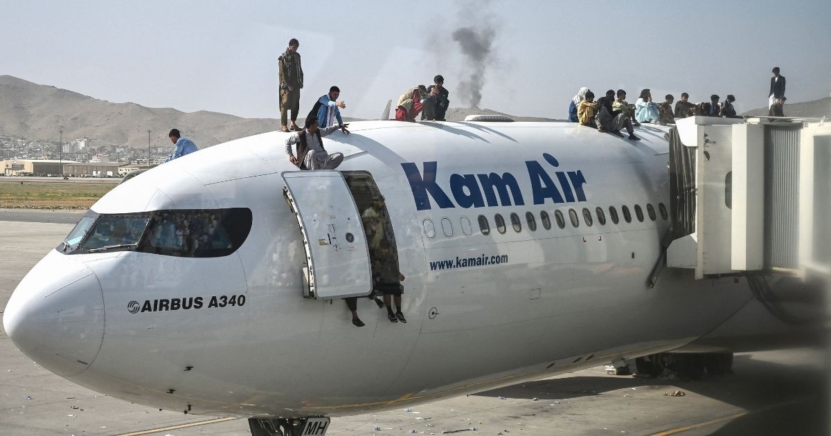 Afghans climb atop a plane at the Kabul airport on Monday.