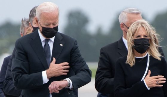 President Joe Biden appears to look down at his watch while standing alongside first lady Jill Biden during the dignified transfer of the remains of fallen service members at Dover Air Force Base in Delaware on Sunday.