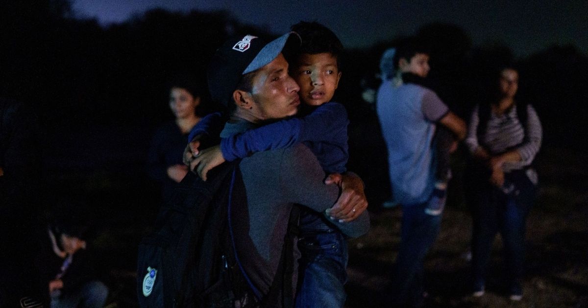 Honduran Eric Villanueva, left, holds his son Eric, 7, while waiting to be led to a United States Border Patrol processing area after crossing the U.S.-Mexico border on a raft into the United States in Roma, Texas, late on July 9, 2021.