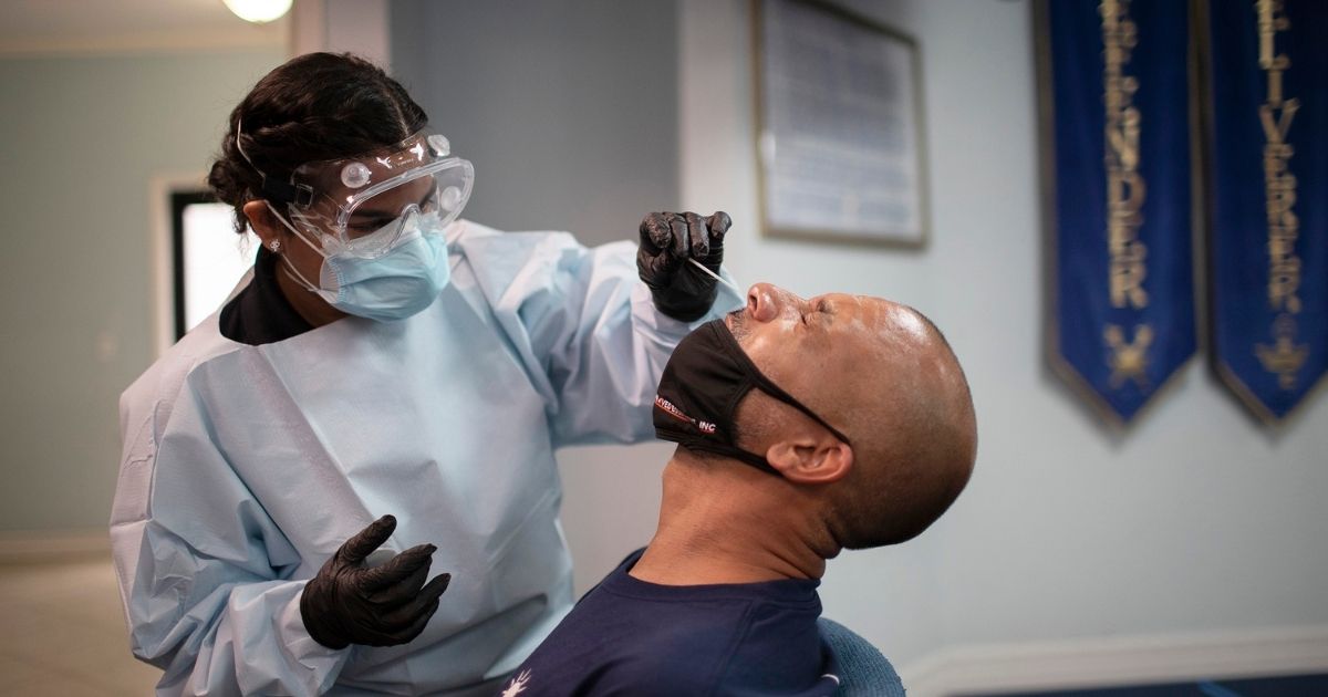 A health care worker tests a man for COVID-19 on July 22, 2020, in Pembroke Park, Florida.