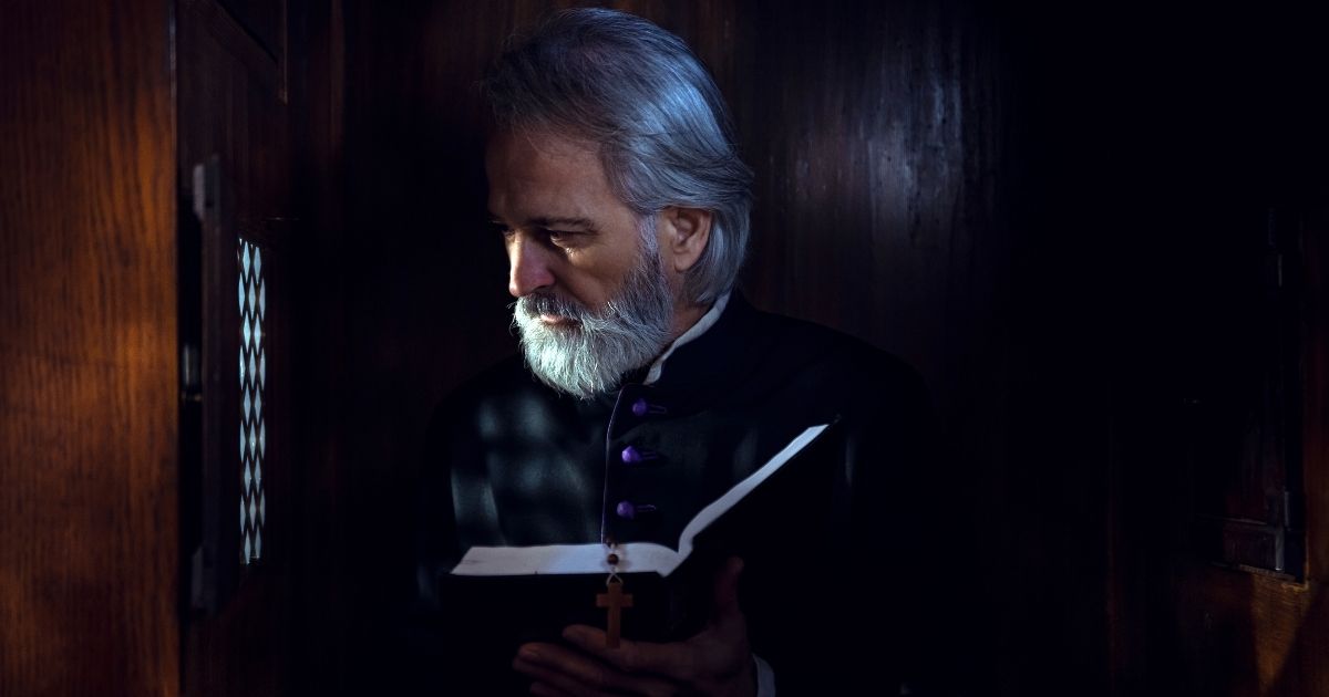 This stock image portrays a Catholic priest sitting in a confession booth. The Catholic Church has removed a conservative priest from ministry seemingly due to his comments asserting that Catholic priests cannot be members of the Democratic Party.