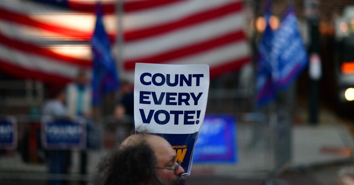 A man holds a placard that reads "Count Every Vote" while demonstrating across the street from supporters of President Donald Trump outside of where votes are being counted on Nov. 9, 2020 in Philadelphia, Pennsylvania.