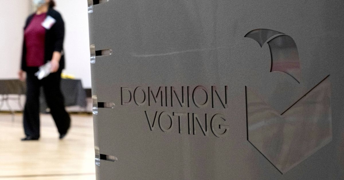 A worker passes a Dominion Voting Systems ballot scanner while setting up a polling location at an elementary school in Gwinnett County, Georgia, on Jan. 4, 2021.