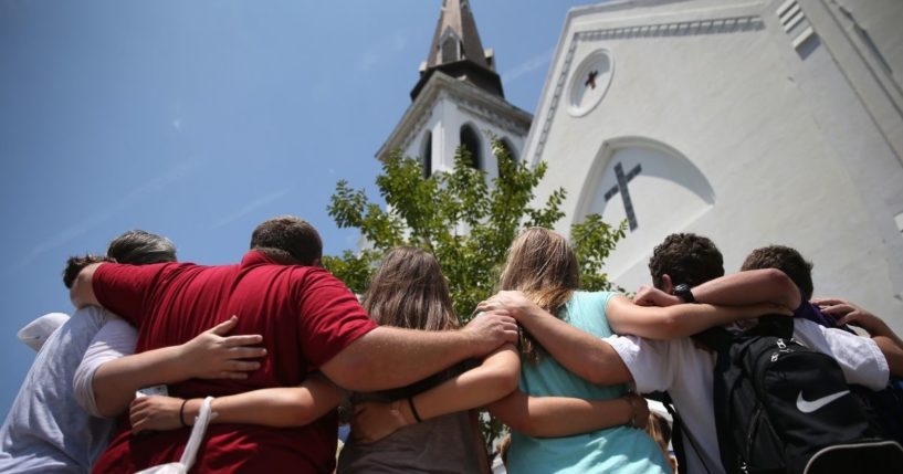 People pray in front of Emanuel African Methodist Episcopal Church on the one-month anniversary of a mass shooting there on July 17, 2015, in Charleston, South Carolina.