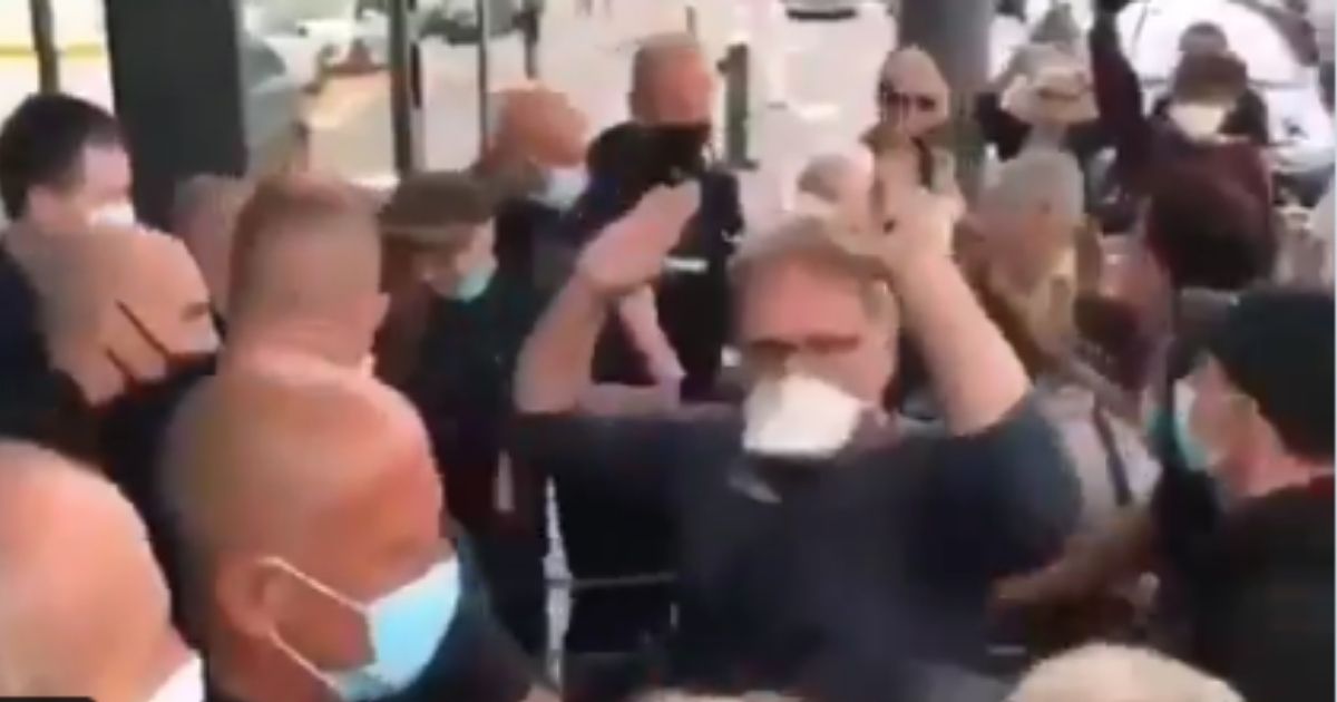 A group of people are blocked by police for not having COVID passports as they attempt to enter a grocery story in France for food on Thursday.