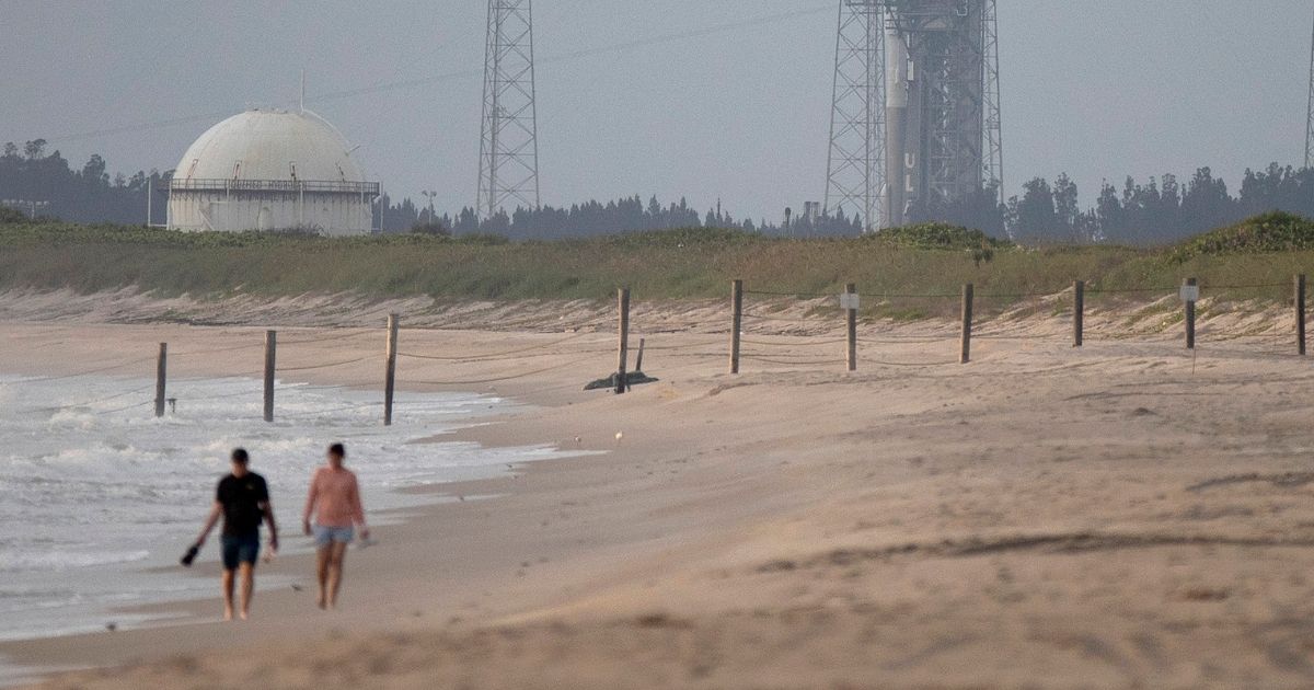 People walk along the beach near the Cape Canaveral Space Force Station on Aug. 3, 2021, in Cape Canaveral, Florida.