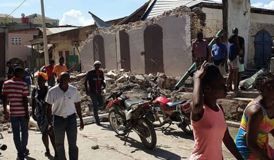 People walk past houses destroyed by an earthquake on Saturday in Jeremie, Haiti.