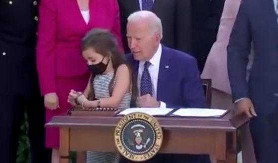 President Joe Biden whispers to a girl during a White House photo op on Thursday.