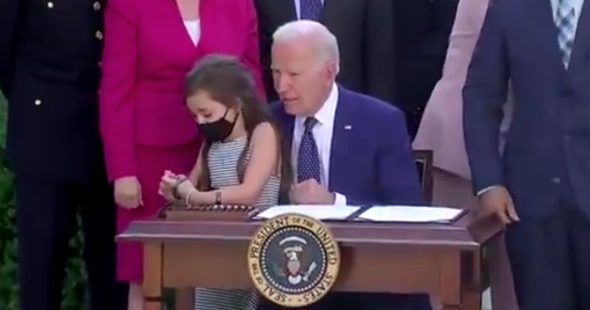 President Joe Biden whispers to a girl during a White House photo op on Thursday.