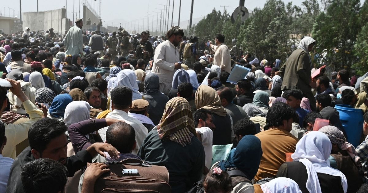 People gather on a roadside near the military part of the airport in Kabul