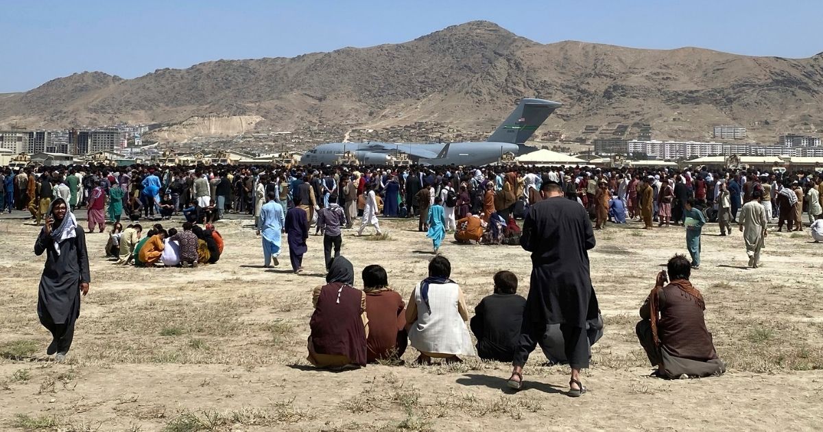 Hundreds of people gather near a U.S. Air Force C-17 transport plane at the perimeter of the international airport in Kabul, Afghanistan, on Monday.