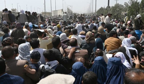 Afghans gather on a roadside near the military part of the airport in Kabul on Friday, hoping to flee from the country after the Taliban's military takeover of Afghanistan.