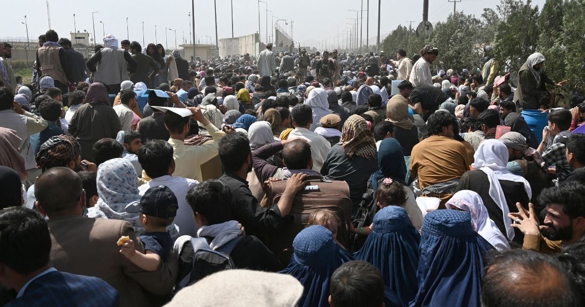 Afghans gather on a roadside near the military part of the airport in Kabul on Friday, hoping to flee from the country after the Taliban's military takeover of Afghanistan.